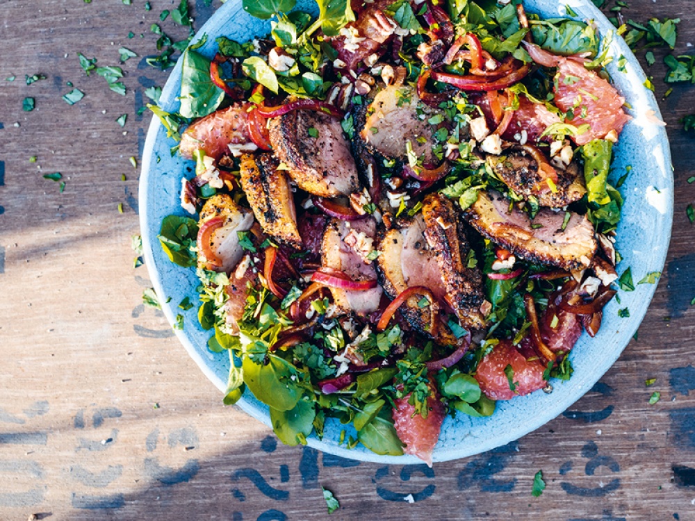 Barbecued duck with salad leaves nuts in a blue bowl