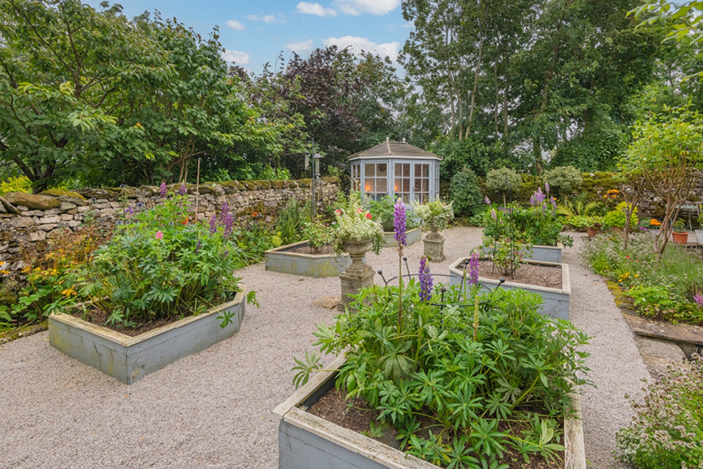 Farmhouse walled garden with a summer house and raised beds
