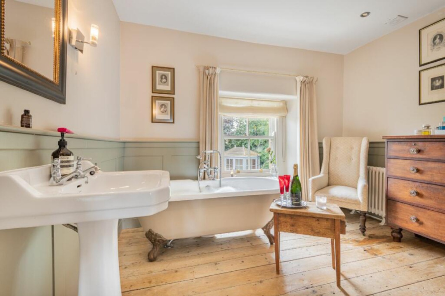 Traditional bathroom with paneling, exposed wooden floors, freestanding bath and feature window